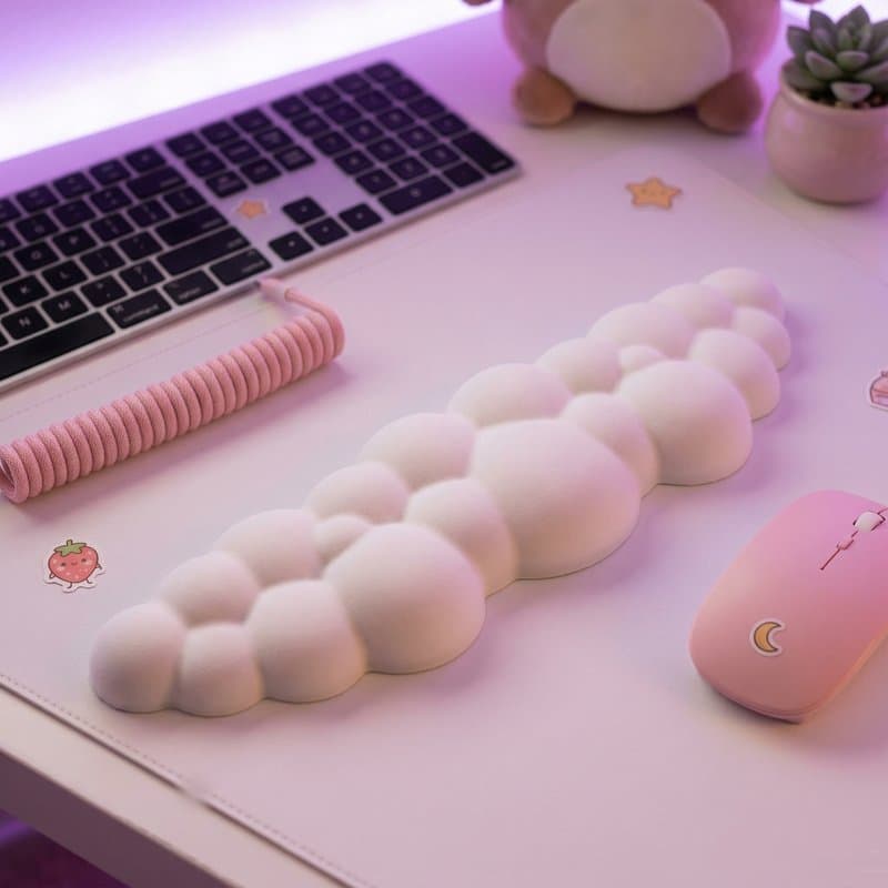 Curated desk accessories including a cloud wrist rest, ceramic mug, and small plant